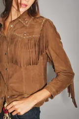 Camisa de gamuza color bordó con diseño de flecos en el frente y hombros, decorada con tachas metálicas. Cuenta con cierre frontal de botones.