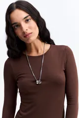 Remera de manga larga ajustada al cuerpo, confeccionada en tejido elástico de poliéster y spándex, con cuello redondo clásico.