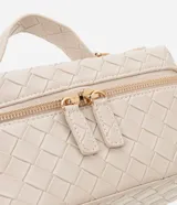 Cartera femenina tipo baú pequeña color beige, con textura tressê, correa de mano fija, cierre por cremallera y asa larga desmontable.