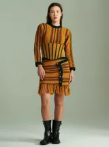 Top tejido de punto color mostaza con rayas horizontales en verde y rojo. Presenta cuello redondo, mangas largas ajustadas, hombreras y un corset integrado con rayas verticales en verde.