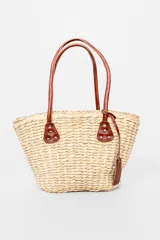 Bolso playero tipo tote de paja color beige con asas de cuero marrón.