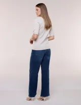 Buzo confeccionado en tejido de punto color beige, de silueta semi entallada, con escote redondo, mangas al codo con detalles metálicos en los puños y terminaciones acanaladas.