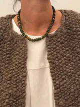 Collar corto de piedras volcánicas negras en la base del cuello, con pequeños detalles en tonos tostados y dorados.
