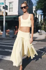 Falda de tiro medio color amarillo claro, confeccionada en tejido de punto elástico con detalle de aplicación combinada y bajo en línea evasé. Cuenta con cierre lateral con cremallera oculta.