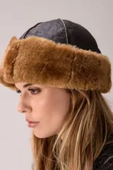 Gorro tipo ushanka de cuero negro con interior y borde de piel sintética en color marrón.