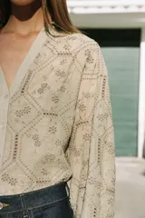 Camisa de cuello solapa con escote en V, manga larga y cierre frontal con botones. Presenta un diseño con bordados perforados en todo la prenda.