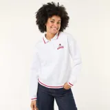 Buzo blanco de estilo polo con cuello abotonado, manga larga y puños con detalle de línea roja. Presenta un bordado pequeño de Minnie Mouse en el pecho.