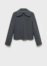 Chaqueta entallada de color gris con diseño de rayas verticales finas. Presenta cuello camisero, cierre frontal de cremallera doble y bolsillo de ribete en el pecho.