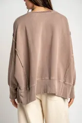 Sweater de algodón peinado con efecto lavado, de corte oversize, cuello redondo y mangas largas con costuras visibles.