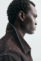 Cazadora de hombre de corte relajado, confeccionada en tejido con algodón de acabado flocado efecto terciopelo lavado, color marrón oscuro con efecto desgastado. Presenta cuello solapa, cierre frontal de cremallera, bolsillo con cremallera en el pecho y bolsillos laterales en la costura de la cadera.