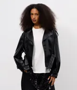 Campera tipo trench coat en PU color negro, de manga larga, con solapa amplia, hombreras decorativas y cinturón ajustable con hebilla en la cintura.