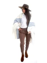Poncho blanco de hilo de algodón grueso, con franjas azules en los laterales, flecos en el ruedo y el escudo nacional uruguayo bordado en la espalda.
