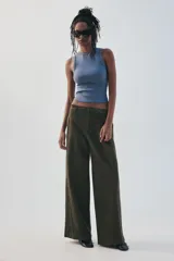 Pantalón verde militar de tiro medio, con bolsillos delanteros, pliegues y tejido con efecto lavado. Cuenta con cierre frontal con cremallera y gancho metálico.