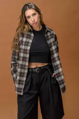 Camisa de corte oversize con diseño a cuadros en tonos marrones, grises y blancos. Presenta cuello clásico, cierre frontal con botones y mangas largas.