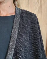 Ruana tejida en algodón con destellos de lurex, de corte amplio y diseño abierto, con textura en punto relieve.