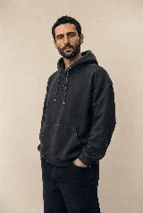 Hoodie de algodón color negro carbón con efecto garment washed, capucha con cordones ajustables y un sutil bordado en el pecho.