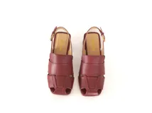 Sandalia de cuero color bordó con diseño de tiras anchas entrecruzadas, punta cuadrada y talón descubierto con pulsera ajustable. Cuenta con taco ancho medio forrado en cuero.