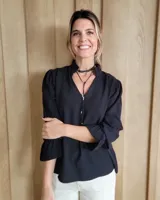 Blusa celeste de algodón con estampado de rayas verticales formadas por pequeños motivos blancos, escote en V con cuello alto fruncido y mangas largas abullonadas con puños amplios.