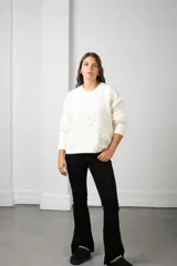 Buzo de punto color blanco, de corte holgado y cuello redondo, con diseño de flores aplicadas con detalles de mostacillas bordadas.