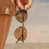 Lentes de sol Sunski modelo Baia Wire, con montura redonda color marrón y lentes color bronce polarizados.