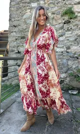 Vestido midi de seda con estampado estilo boho, escote en V, mangas 3/4 con volados y detalle de franja central contrastante. Presenta una cintura elástica y ruedo con volado.