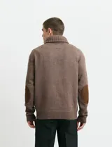 Cardigan de punto color marrón con cuello esmoquin, cierre frontal con botones y presilla superior. Presenta mangas largas con coderas en contraste y bolsillos frontales de ribete.