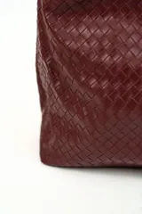 Cartera tipo hobo de cuero sintético bordó, con diseño trenzado y asa integrada.