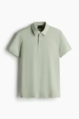 Remera polo de manga corta en punto de algodón liviano, color verde pálido, con cuello y tapeta de botones. Corte ajustado al cuerpo.