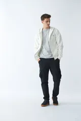 Campera de felpa color blanco hueso, con capucha y cordón ajustable, cierre frontal con cremallera, bolsillos laterales, logo y arte estampado en el pecho.