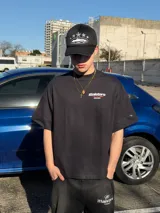 Remera oversize negra con diseño gráfico estampado en el pecho y en la espalda con inscripciones y líneas rojas.