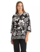 Blusa de seda fría con estampado floral en blanco y negro. Presenta cuello a la base, mangas tres cuartos amplias y ruedo con abertura lateral decorada con botones.