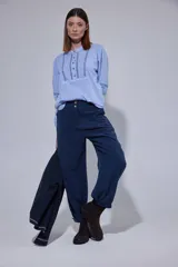 Pantalón de corte holgado tipo bombacha, confeccionado en Tencel, con pinzas frontales, cierre de botones dorados en la cintura y ruedo ajustable con botón.