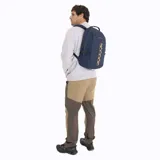 Mochila unisex Merrell modelo Trout Basic, color azul marino, con capacidad de 25 litros. Presenta un panel frontal con tiras de ajuste elásticas de color beige y correas de compresión laterales con hebillas negras.