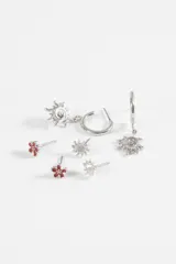 Set de tres pares de aros de metal plateado. Incluye un par de aros tipo stud con forma de flor con centro esmaltado en rojo, un par de aros tipo stud con forma de sol pequeño y un par de aros tipo argolla con dije colgante en forma de sol con diseño espiral.
