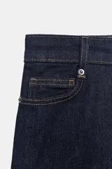 Jeans de tiro alto con corte wide leg y largo completo. Presenta diseño de cinco bolsillos, trabillas en la cintura y cierre frontal con cremallera y botón, con un acabado de efecto lavado.