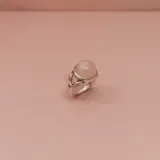 Anillo de plata 925 con una piedra central redonda de cuarzo rosa. La montura presenta un diseño trenzado o entrelazado en la banda.