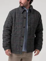 Chaqueta de lana Harris Tweed color gris con patrón de tartán, cuello camisero, cierre frontal de botones y bolsillos aplicados.