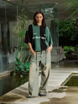 Pantalón de jean de lavado claro (oxido), corte ancho y tiro bajo, con cordones ajustables a la vista en la cintura y bordado en el frente.