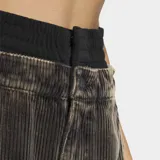 Pantalón de corte holgado confeccionado en tejido de corderoy, con diseño de cintura alta y cierre frontal con botones. Presenta una estética urbana con franjas laterales características de la marca.