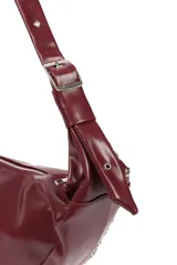 Cartera negra en forma de media luna, con cierre superior y ojales metálicos plateados en el borde.