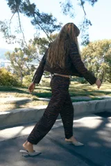 Pantalón de tiro medio con corte barrel, caracterizado por su silueta holgada en cadera y muslos que se estrecha hacia el tobillo. Presenta estampado animal print, bolsillos delanteros y cierre frontal con cremallera, botón y gancho.