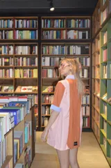 Camisola corta con cuello camisero y mangas cortas, con diseño a rayas verticales en tonos naranja, rosa y celeste.