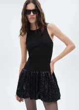 Vestido corto con cuerpo entallado sin mangas y cuello redondo, combinado con una falda estilo globo con acabado de lentejuelas brillantes.
