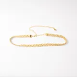 Cinto fino de cadena trenzada en color dorado, con cierre de mosquetón y cadena de alargue ajustable.