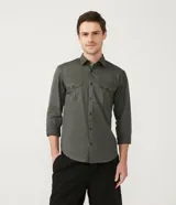 Camisa verde militar de manga larga en sarga de algodón, con cuello clásico, cierre frontal abotonado y dos bolsillos con solapa abotonada en el pecho.