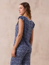 Conjunto de pijama marca René Rofé, compuesto por remera de mangas cortas con escote en V abotonado y pantalón capri con cintura elastizada. Diseño estampado con flores azules sobre fondo blanco.