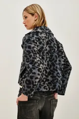 Tapado corto de corte sastre con solapas amplias y cierre frontal cruzado de doble botonadura. Presenta un estampado animal print en tonos grises y negros, con textura suave y mangas largas.