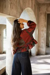 Kimono de lino con diseño patchwork en tonos rojizos y oscuros, con cuello camisero, cierre frontal de botones, mangas largas abullonadas y ruedo con volados.