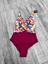Malla entera plus size con diseño combinado, parte inferior negra y parte superior con estampado floral en tonos amarillos, rojos y celestes, con escote en V cruzado.