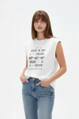Musculosa blanca de algodón con cuello redondo y estampa frontal en tono oscuro con texto y diseño de caballos.